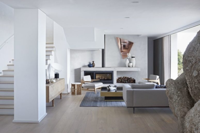 The living room is all-white, with firewood storage, geometric details and super elegant furniture