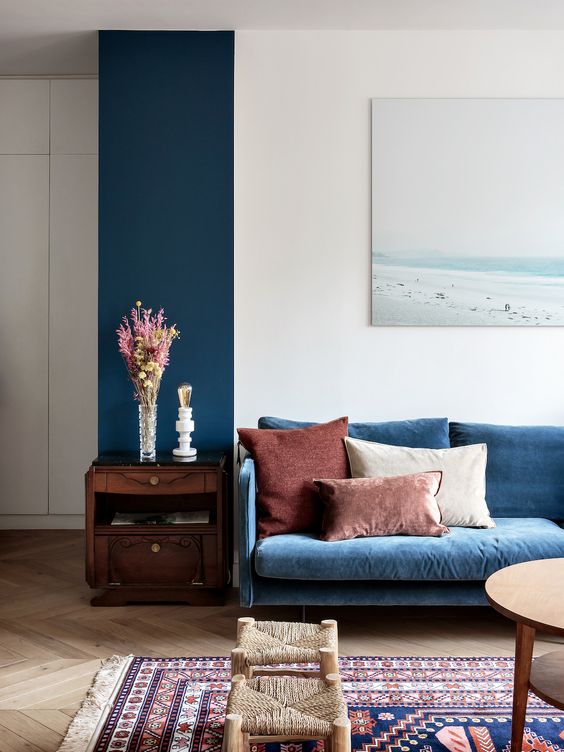 a classic blue sofa and a matching accent wall is a gorgeous idea that will bring a calm and cozy feel to the space