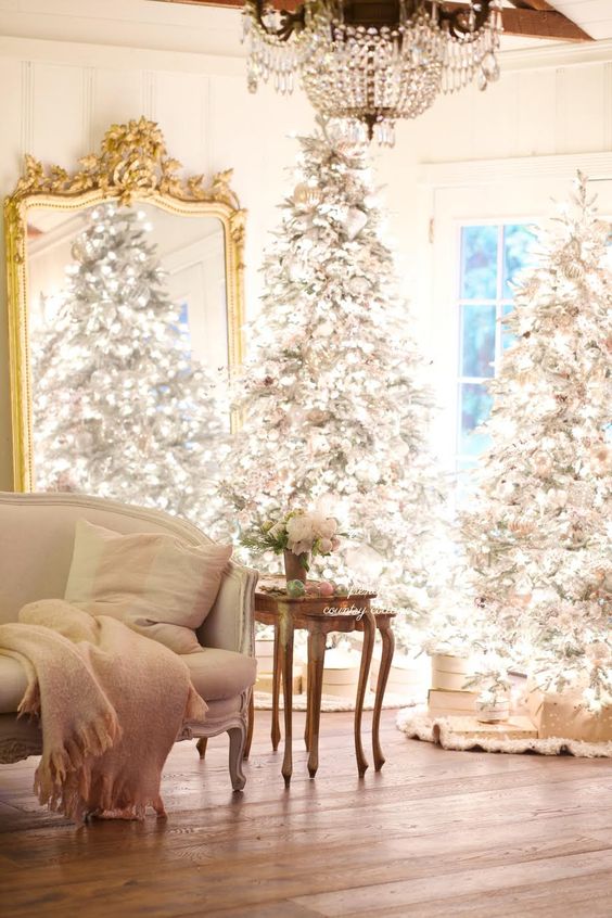 a duo of flocked Christmas trees with lots of lights and neutral and silver ornaments is amazing for a chic space