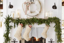 09 a lush evergreen garland on the mantel, chunky knit white stockings for a pretty coastal Christmas space