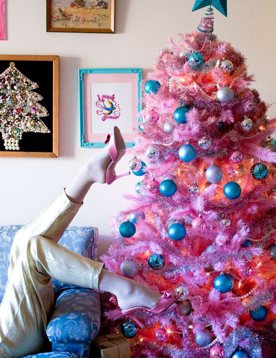a bright pink Christmas tree with metallic and blue ornaments and lights looks pretty and retro