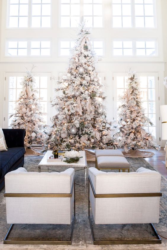 a trio of large flocked Christmas trees with lights, neutral and metallic ornaments for a winter fairy-tale in the space