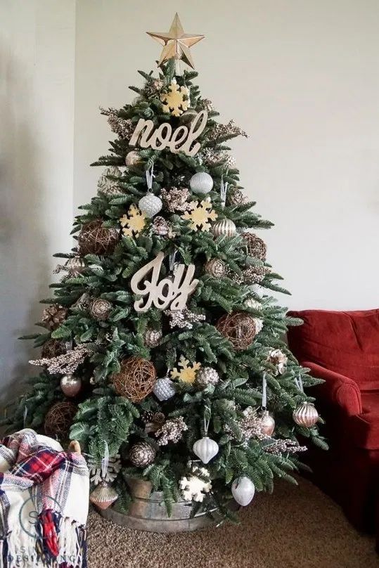 a farmhouse Christmas tree with metallic and oversized vine ornaments, wooden signs and snowflakes plus a galvanized bucket base