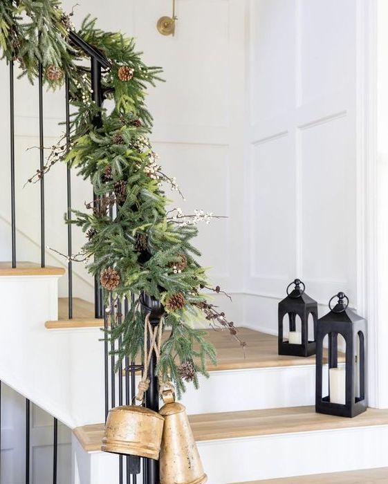 a lush evergreen garland with pinecones and berries plus large bells will make your staircase super festive