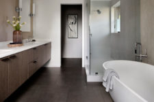 13 The bathroom features a large floating vanity, a shower space and an oval tub