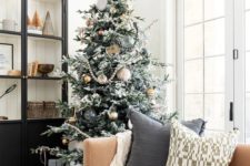 13 a flocked Christmas tree with sheer, gold and black ornaments including oversized ones and a star topper