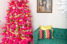 13 a hot pink Christmas tree with green and gold ornaments, pompom garlands and a quirky topper