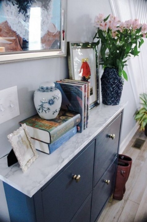 a navy IKEA Hemnes shoe cabinet with a marble contact paper top and cool geometric knobs looks very chic and contemporary