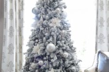 14 a flocked Christmas tree with silver and silver glitter usual and oversized Christmas ornaments looks frozen