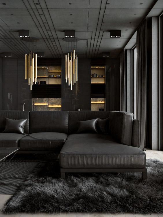 a luxurious dark living room with a large black sectional sofa, a faux fur rug, statement gold chandeliers and raw concrete