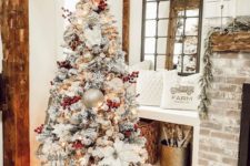 15 a flocked farmhouse Christmas tree with red berries, metallic ornaments including large ones and fabric blooms