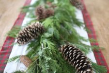 16 a lush greenery garland with pinecones is a cool table decoration for Christmas