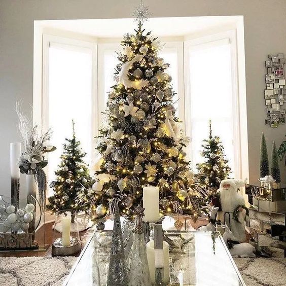 a trio of elegant and chic Christmas trees decorated with lights and white and silver ornaments and feathers