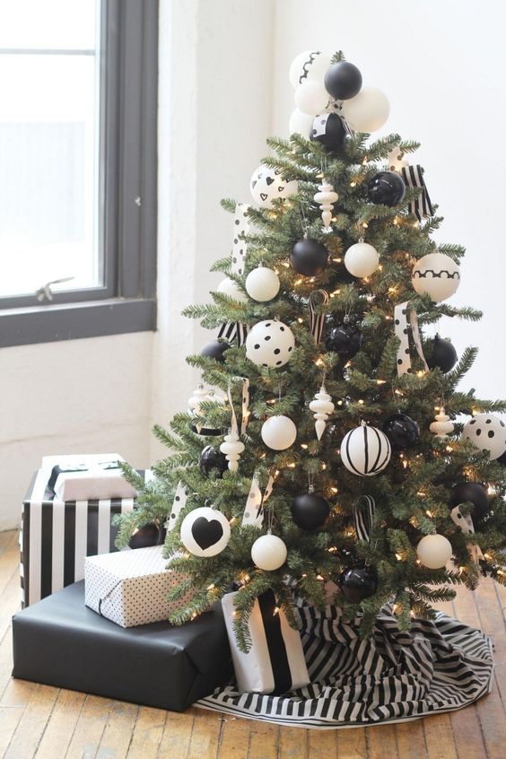 a stylish modern Christmas tree with lights and printed oversized black and white ornaments plus a striped skirt