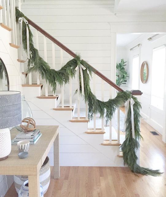 an evergreen garland with neutral silk bows to decorate the railing is a stylish and beautiful idea