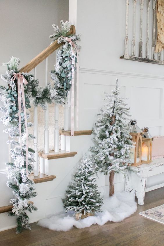 Two non decorated flocked Christmas trees and a matching garland attached to the railing are a gorgeous idea