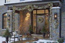 22 a pale evergreen and greenery garland with lights covering the porch and matching posies and wreaths