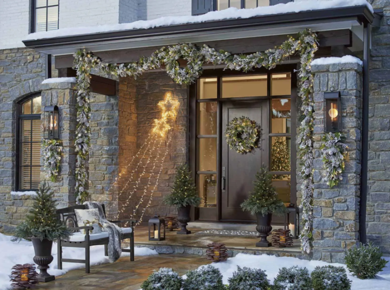 a pale evergreen and greenery garland with lights covering the porch and matching posies and wreaths