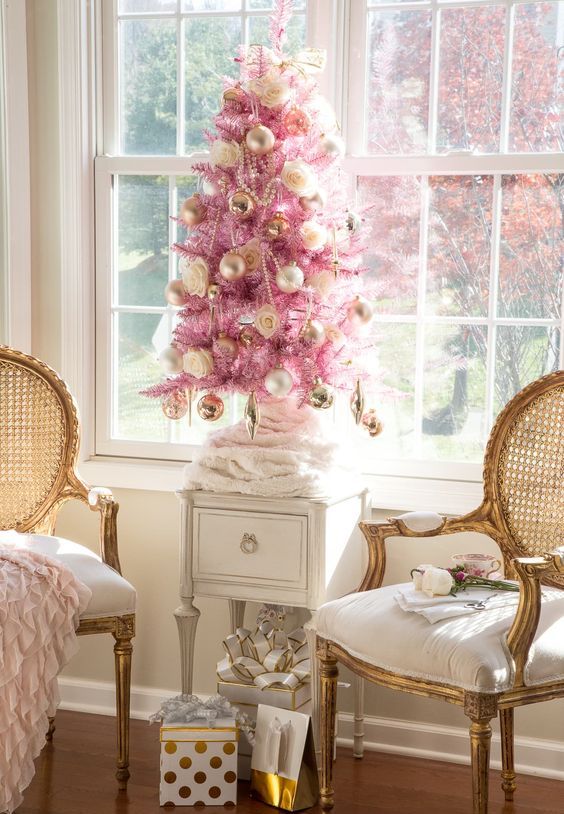 a pink Christmas tree with gold ornaments, gold beads and roses plus a bow on top looks refined and vintage-like