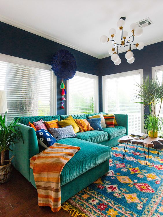 a colorful and fun living room with bright furniture, rugs, an artwork and lots of pillows