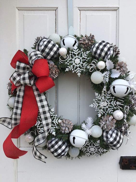 a frozen Christmas wreath with large bells, snowflakes, pinecones and a red and buffalo check bow