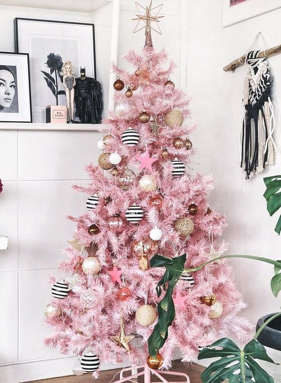 a pink Christmas tree with vine, black and white ornaments, copper and gold ones and a star topper