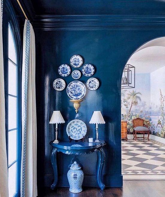 a space fully painted in classic blue - the walls, the ceiling an even a matching console table plus blue and white decorative plates