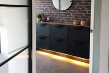 a black IKEA Trones piece attached to the wall, with a stained countertop and built-in lights underneath