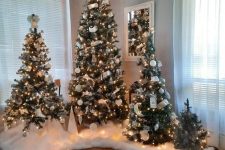 a cluster of Christmas trees with faux snow cover, white ornaments and ribbons in the corner