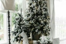 a cool flocked Christmas tree display with lights and some Christmas decor under the trees