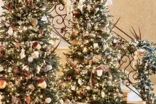 a duo of gorgeous and luxuriously decorated Christmas trees with lights, acorns and other ornaments
