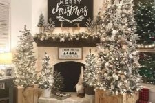 a farmhouse living room with multiple flocked Christmas trees with lights, pinecones, snowflakes and ribbons