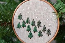 a lovely embroidery hoop Christmas ornament with embroidered trees and snow is a cool rustic decoration for the holidays