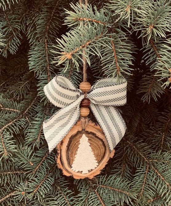 A pretty and all natural Christmas ornament of a wood slice, wooden beads, a striped bow and a white painted tree is lovely