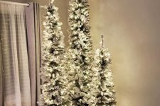 a stylish Christmas tree cluster, flocked trees with lights, is a super cool and catchy idea for holiday decor