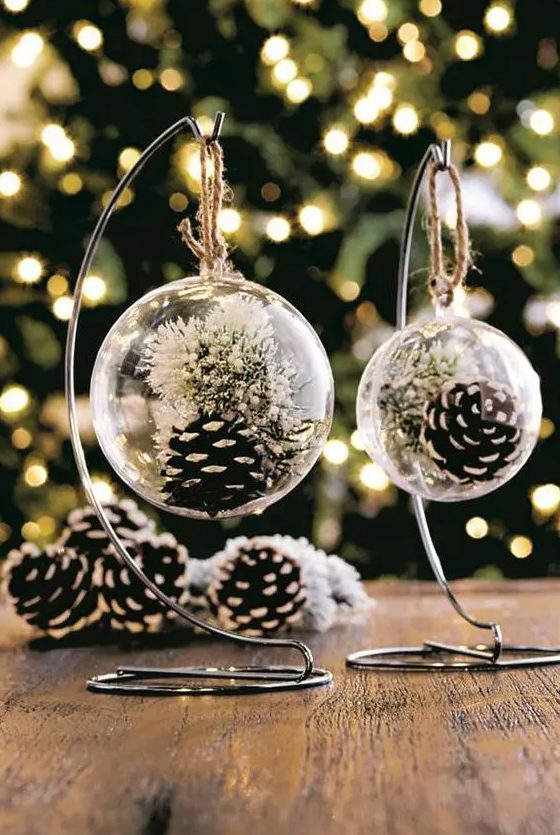 clear glass Christmas ornaments with snowy pinecones and white blooms inside will be a nice solution for boho or rustic holiday decor