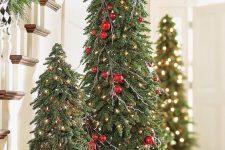 multiple Christmas trees with branches, lights, red ornaments and poinsettias are amazing