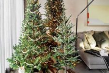 multiple Christmas trees with burlap, gift boxes, a basket and some lights is a cool decor idea that is non-typical