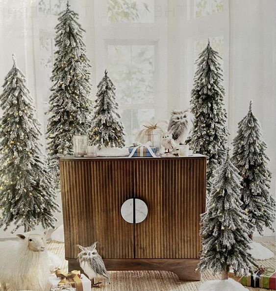 Multiple flocked Christmas trees and some faux owls will turn your entryway into a snowy fairy tale