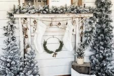 multiple flocked Christmas trees in crates and baskets, with a matching garland on the mantel and some mirrors