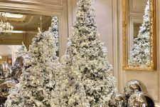 multiple flocked Christmas trees with lights and silver balls around are amazing, they create a chic and elegant look