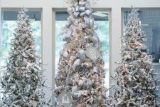 multiple flocked Christmas trees with lights, ornaments, ribbon, bows and snowy branches are adorable