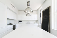 02 The kitchen is purely white, with vintage metal lamps and some stylish appliances