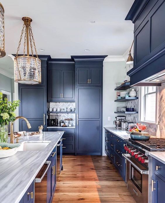 a classic navy kitchen with sleek cabinets, metal handles, stone countertops and chic and refined lamps