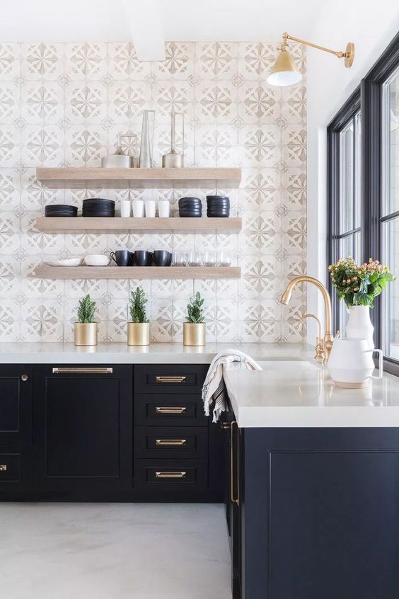 a navy kitchen with a thick white countertop, gold fixtures, thick open shelving and mosaic tiles