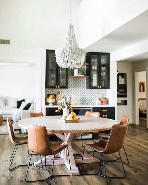 a round wooden table with leather chairs and a statement bead chandelier create an informal dining space