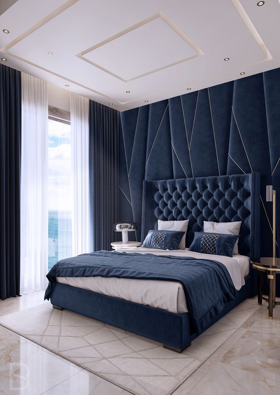 navy velvet and a statement headboard wall make the space wow, and gold touches add to this luxury