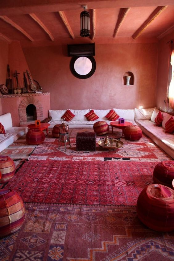 a bold red space done with Moroccan touches - patchwork poufs, striped pillows, a large hearth with musical instruments on the mantel