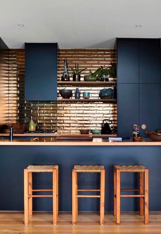 a sleek navy kitchen with a copper tile backsplash, matching countertops and chairs