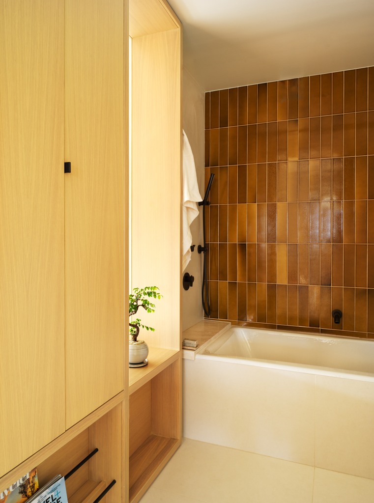 The bathroom features much storage space hidden within the wardrobes and tiles of a very quirky earthy shade